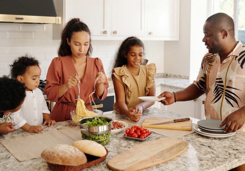 A diverse family preparing a meal together in a bright, modern kitchen setting.
